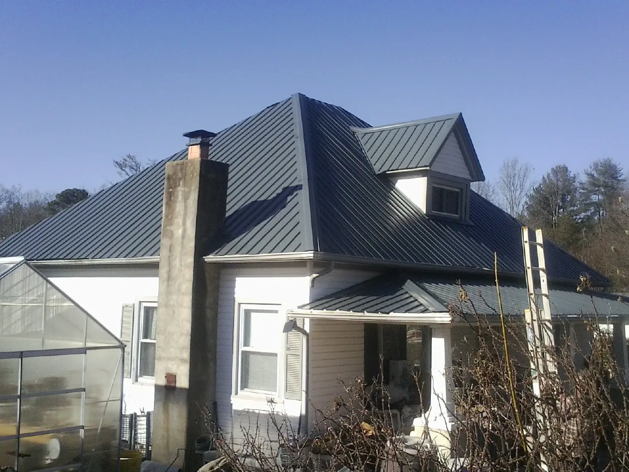 Dark blue standing seam metal roof on a white farmhouse with dormer — Slate & Tile Roof Repair by Roofing Brothers in Monson