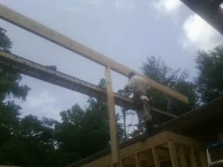 Carpenter setting a ridge beam over a new addition frame — Ice Dam Removal by Roofing Brothers in Monson