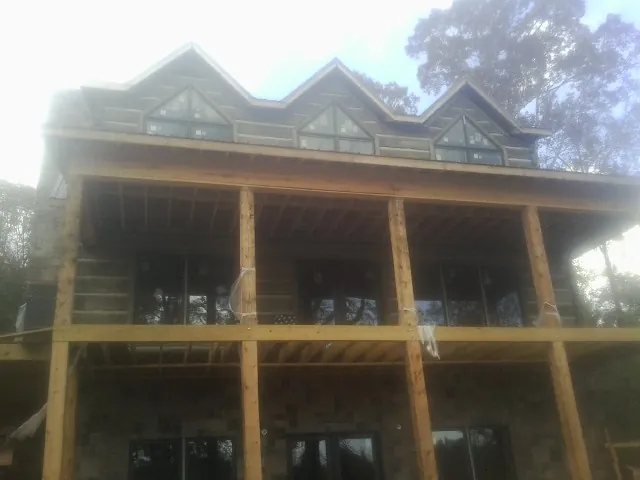 Dormers and porch framing on a large log home under construction — Roof Coating work by our crew in Monson