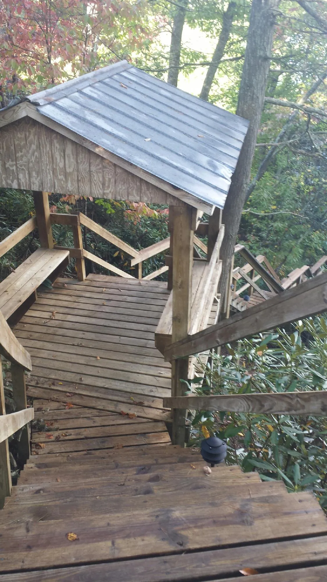 Metal roofed shelter over wooden steps on a wooded walkway — Skylight Repair & Installation work by our crew in Monson