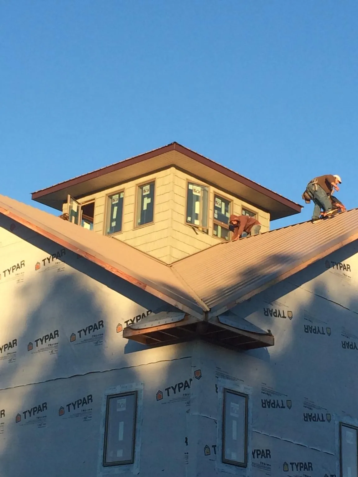 Roofers working around a rooftop cupola on a new metal roof at sunset — Roof Waterproofing in Monson by Roofing Brothers